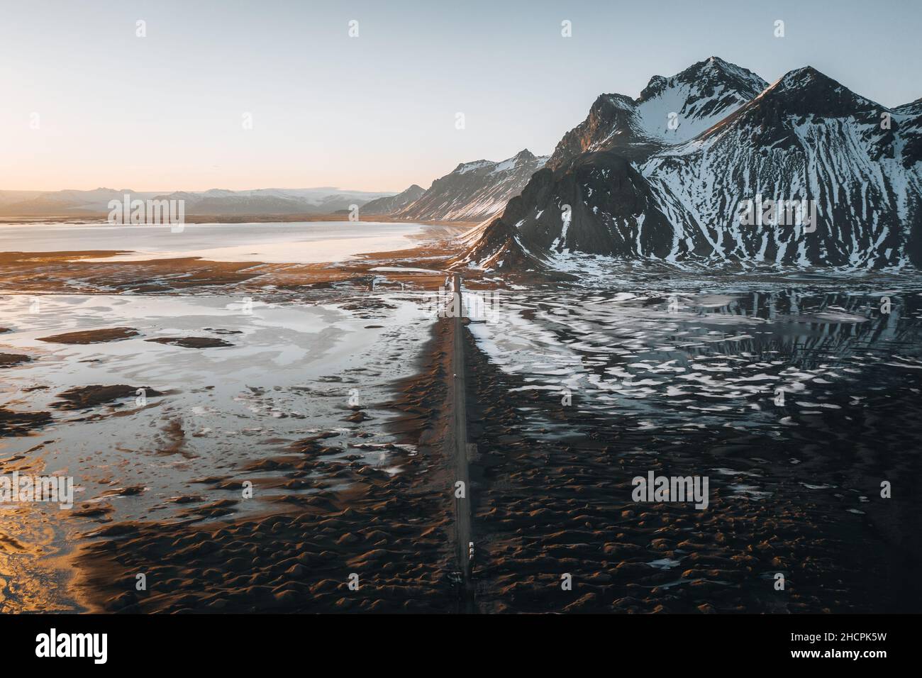 Aerial drone panorama of gravel road at sunset with Vestrahorn mountain and stokksnes beach in Iceland in the background. Winter scenery with snow and Stock Photo
