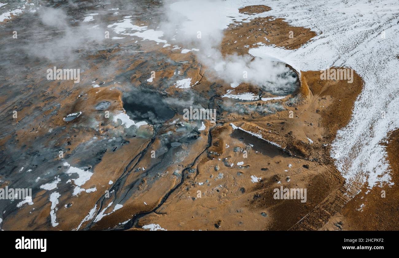 Aerial Drone panorama with hot steam coming from the ground. Hverir is geothermal area in Myvatn. Landscape covered with snow and orange ground. Stock Photo