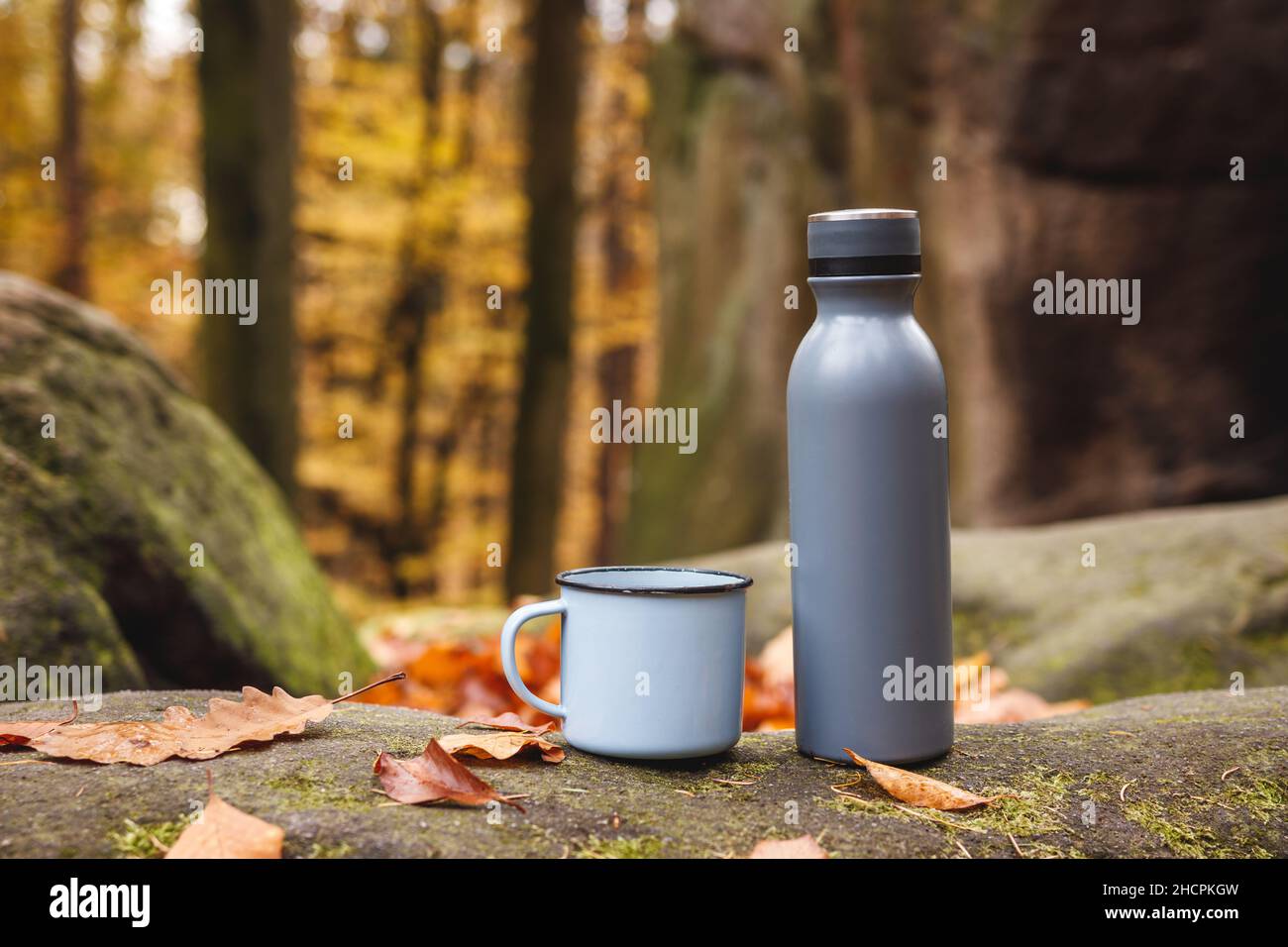 https://c8.alamy.com/comp/2HCPKGW/thermos-and-travel-mug-in-autumn-forest-insulated-drink-container-on-rock-refreshment-during-hiking-2HCPKGW.jpg