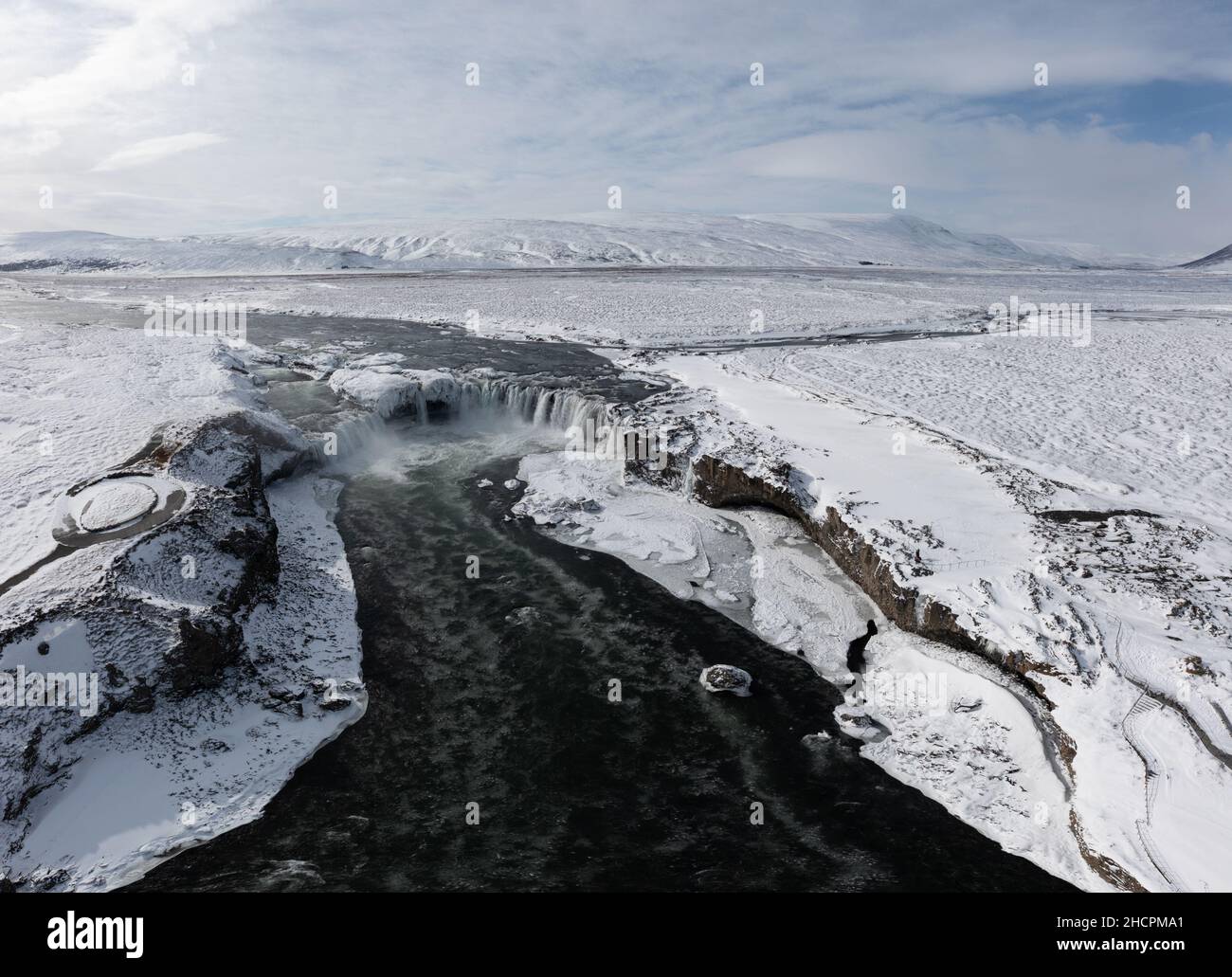 Drone shot of Godafoss waterfall, Iceland, taken from a high angle. Aerial view of the powerful cascade, river and snow covered rocks. Late autumn Stock Photo