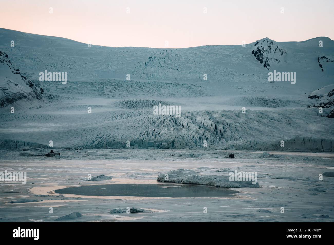 Frozen Fjallsarlon glacier lagoon in Vatnajokull National Park druing sunset with blue sky in winter. Iceland nature affected by global warming. Stock Photo