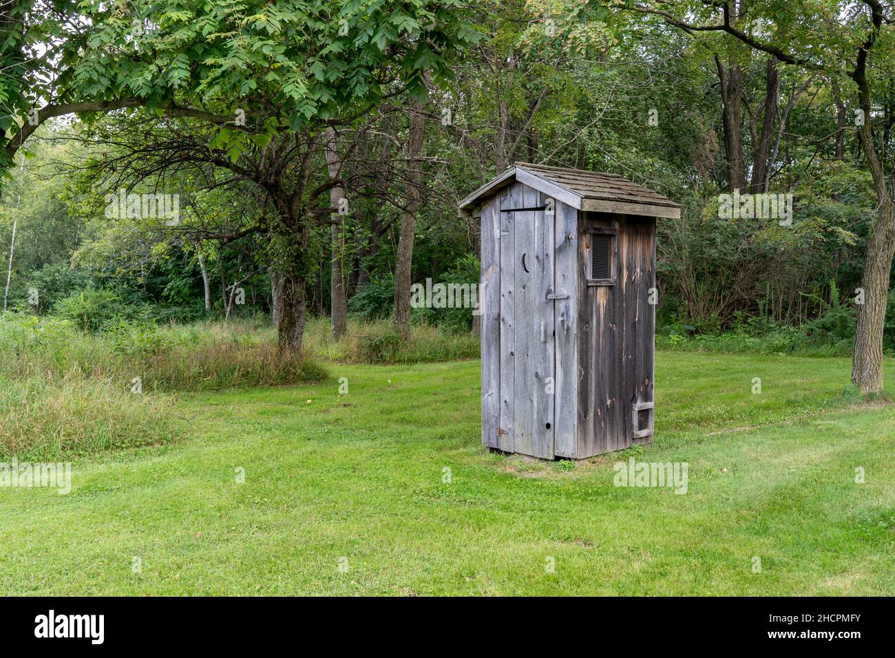 An old outhouse or potting shed on a green lawn. Stock Photo
