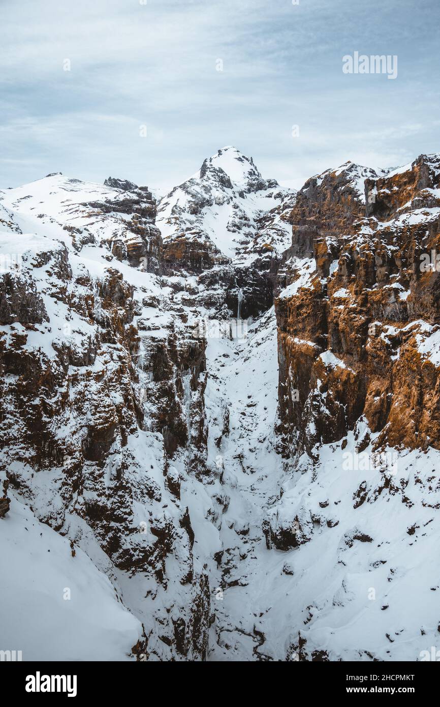 Secret canyon named Mulagljufur canyon in South Iceland. Waterfall below mountain top in winter and snow landscape. Top tourism destination. South Stock Photo