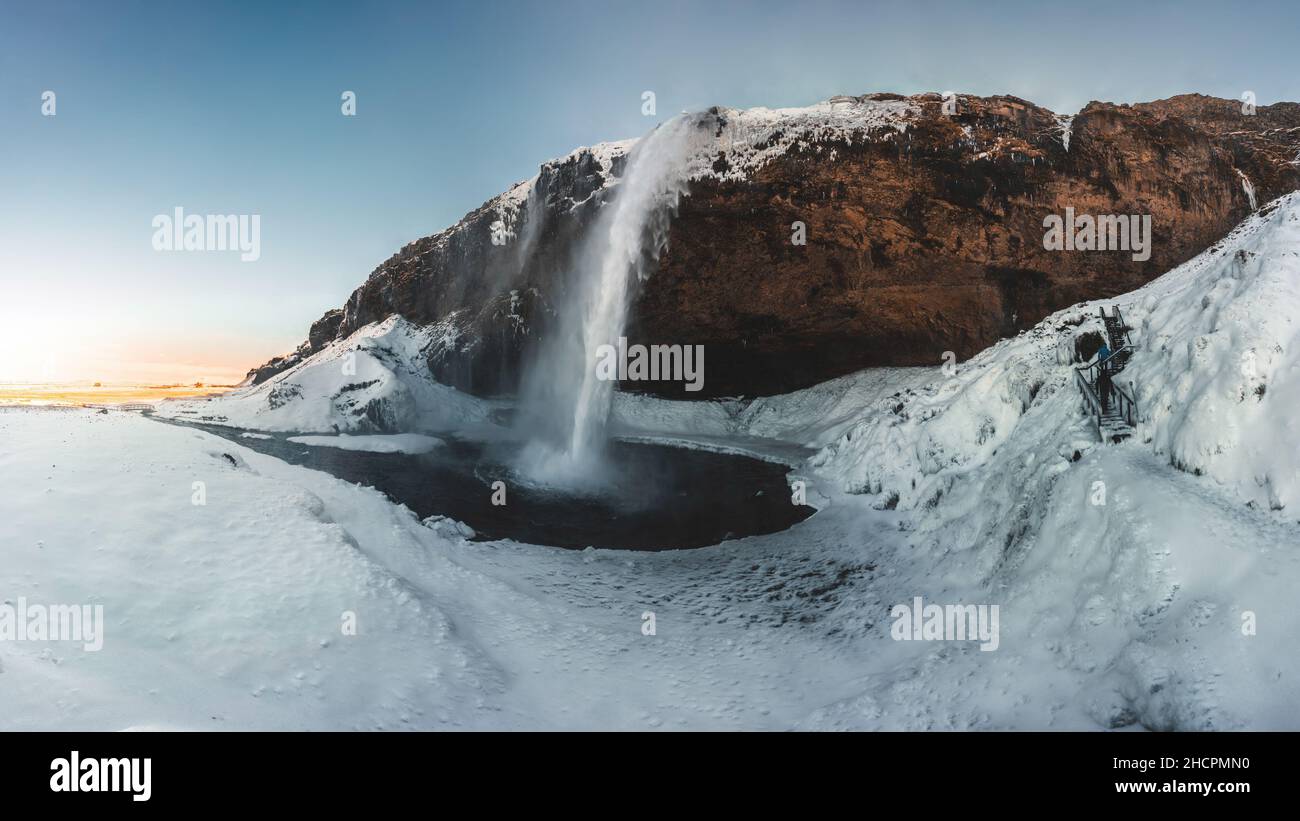 Seljalandsfoss waterfall in Iceland during winter with blue sky and snow and frozen landscape. Stock Photo