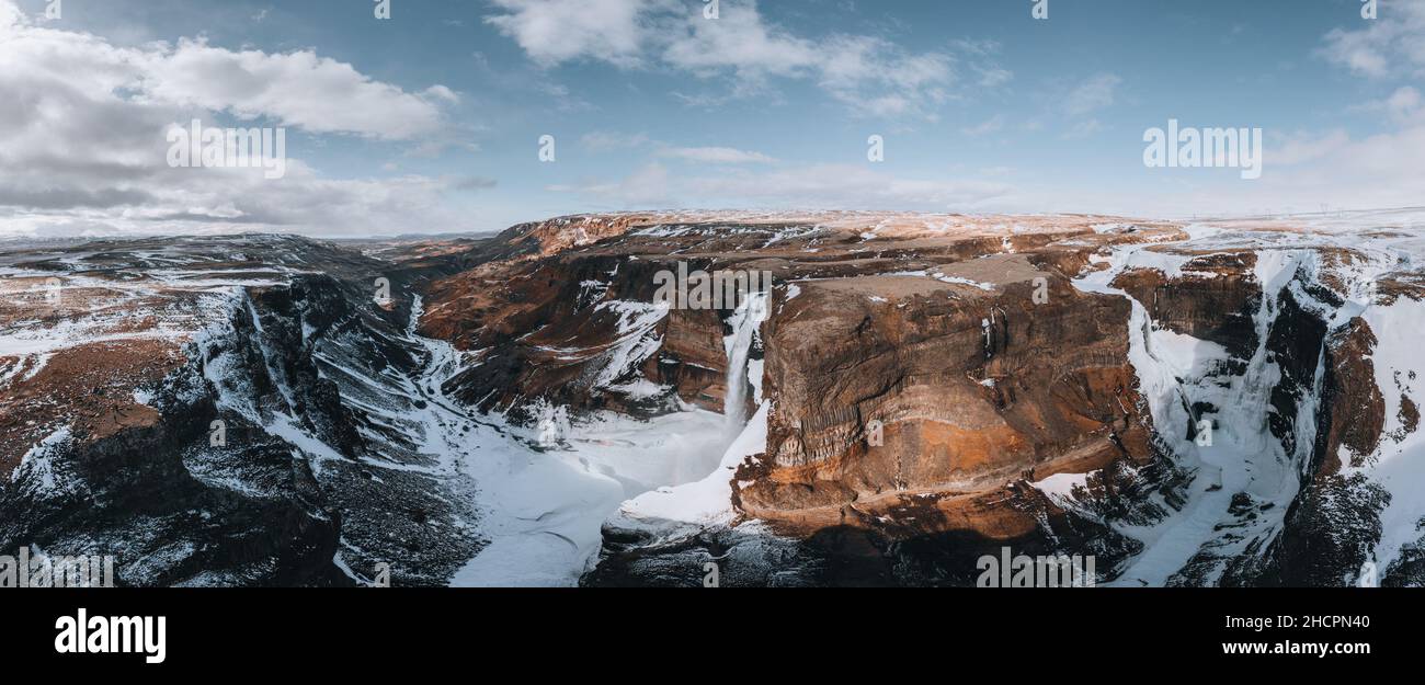 Aerial drone view of Haifoss waterfall in Iceland during Winter in the Highlands. Blue sky and clouds in snow. Stock Photo