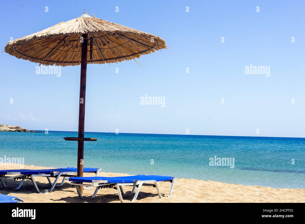 Two sun beds under sun umbrella at the beach. Zephyros beach. Greece