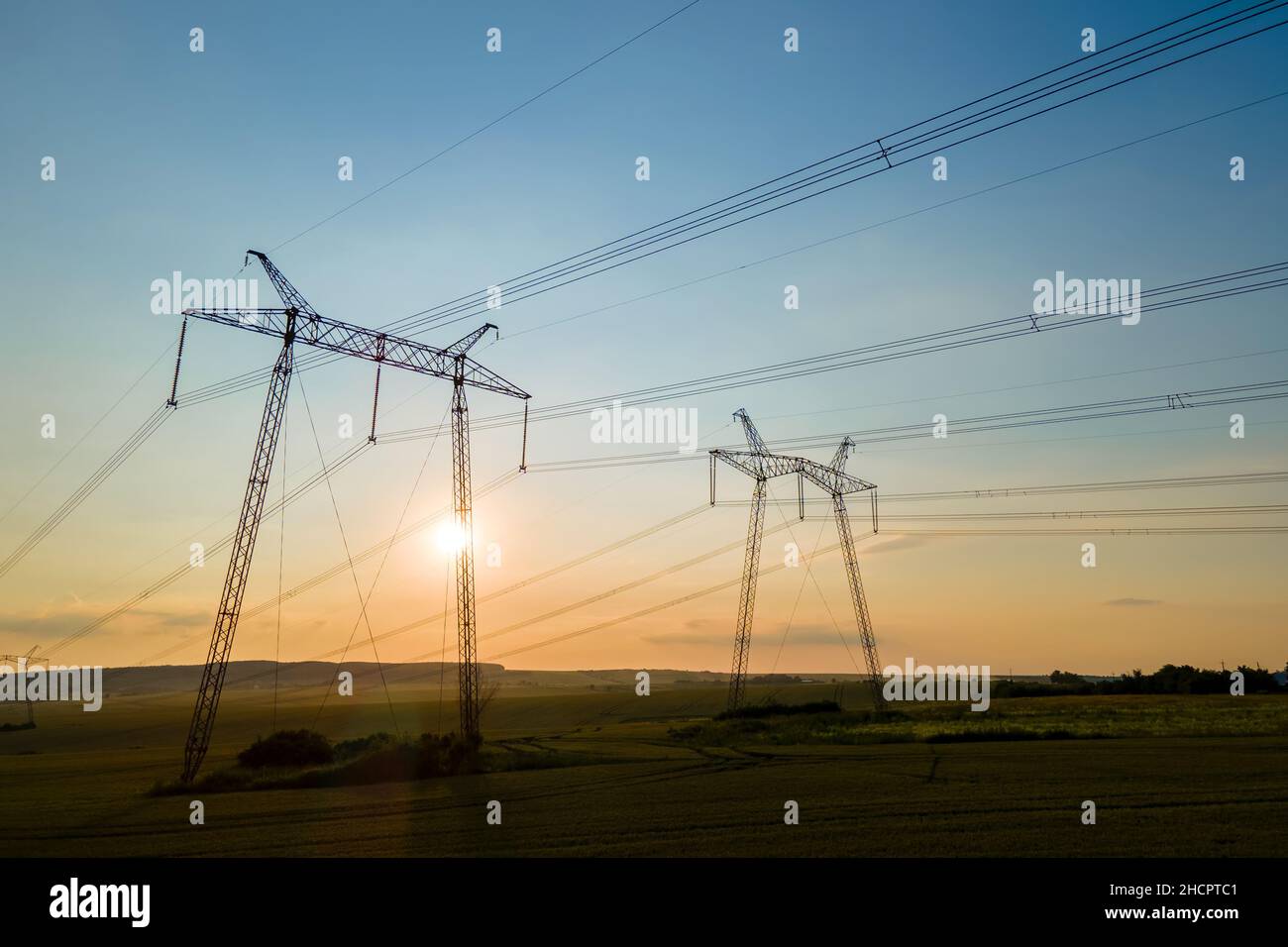 Dark silhouette of high voltage towers with electric power lines at ...