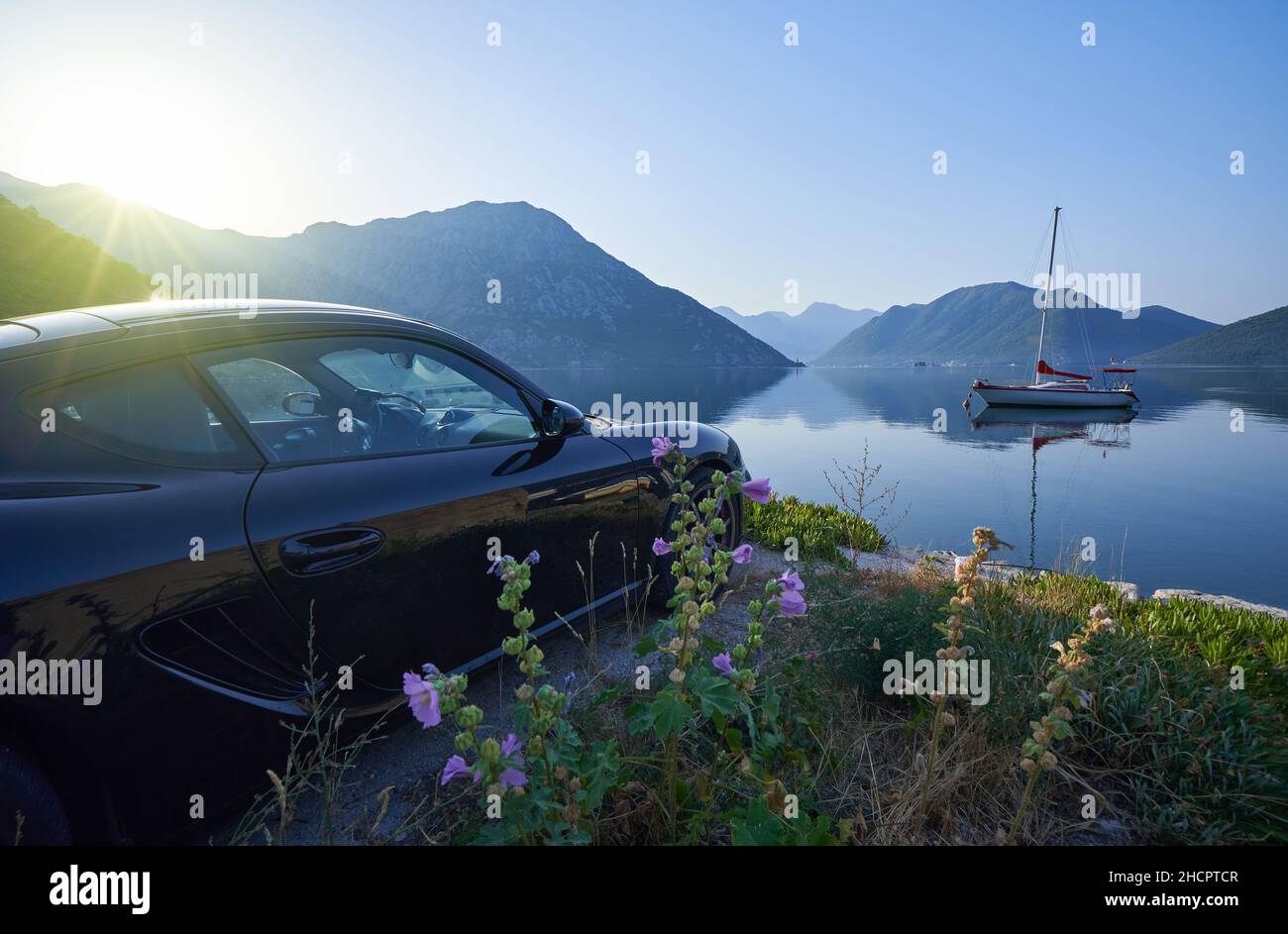 Sports car by the sea with mountain views, morning seascape with car. Stock Photo