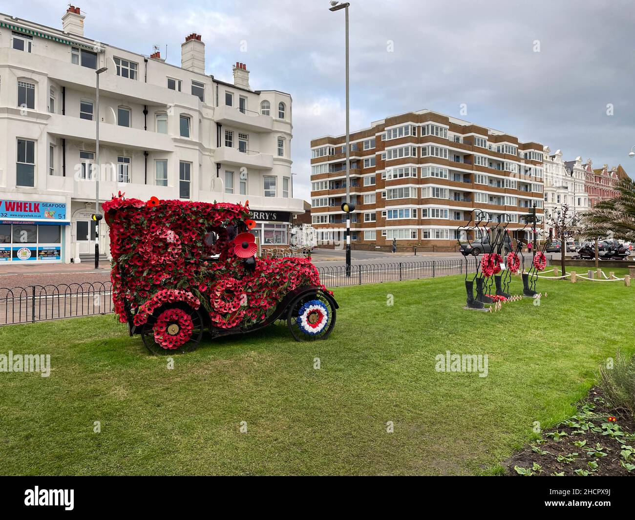 A classic car covered in poppies for Remembrance Day.Metal silhouettes of soldiers with wreaths Stock Photo