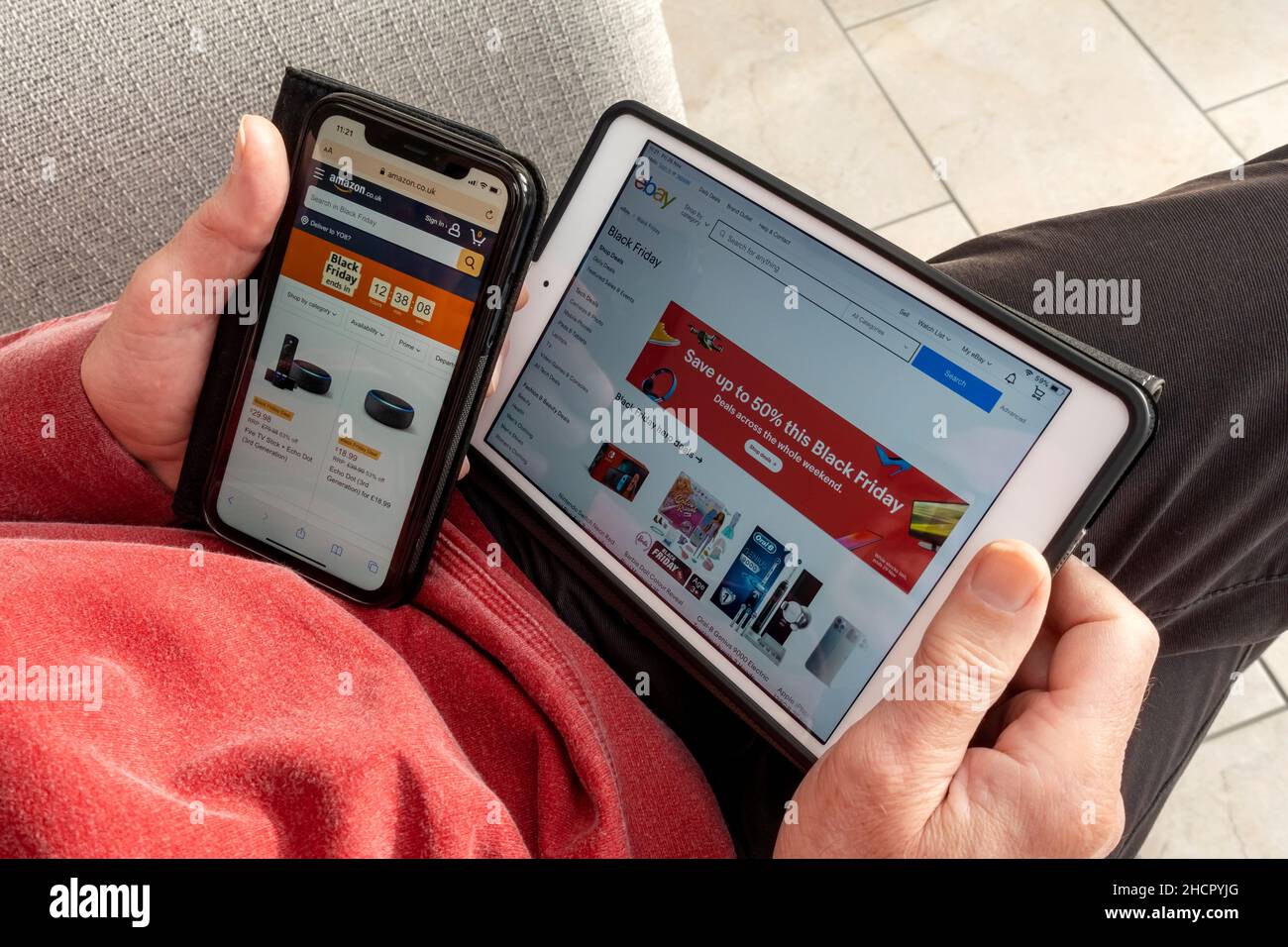 Close up of man browsing and ordering goods on Black Friday website on iphone and ipad tablet England UK United Kingdom GB Great Britain Stock Photo