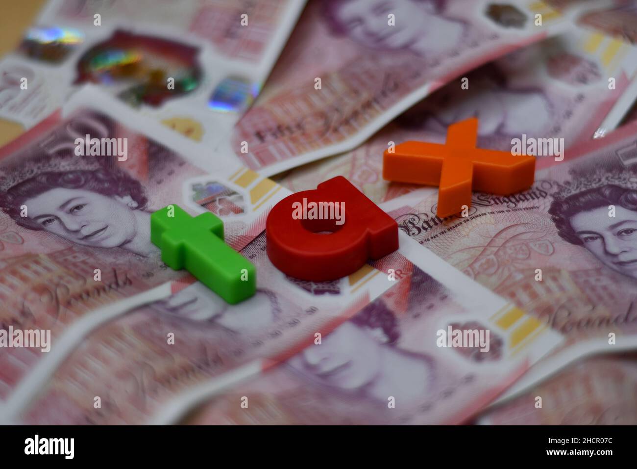 Plastic letters with the word Tax, taxes, payment concept, on a bed of fifty £50 pound notes, sterling Stock Photo
