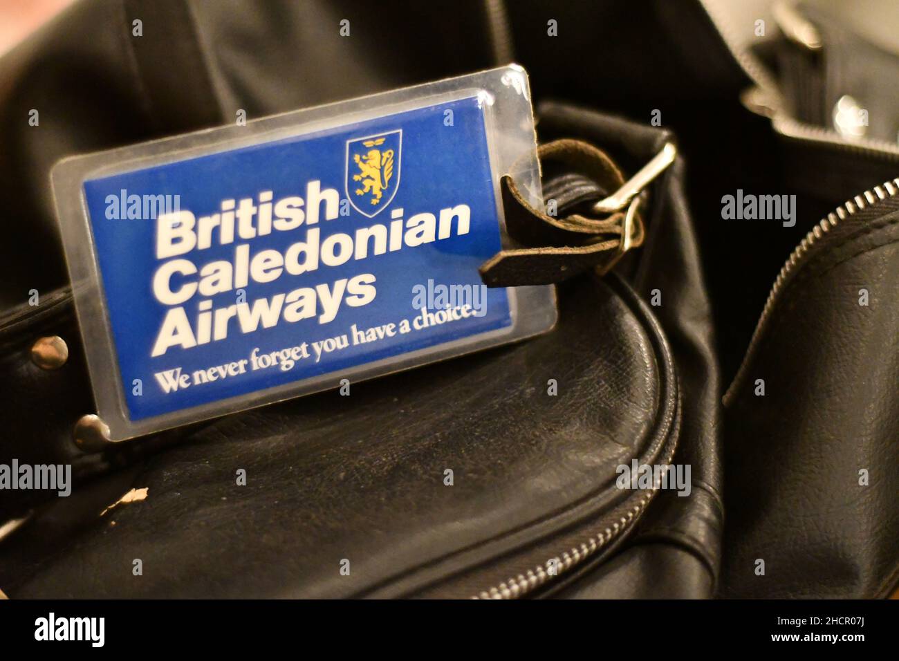 A British Caledonian Airways travel badge, tag, on a black leather travel bag with the slogan we never forget you have a choice Stock Photo