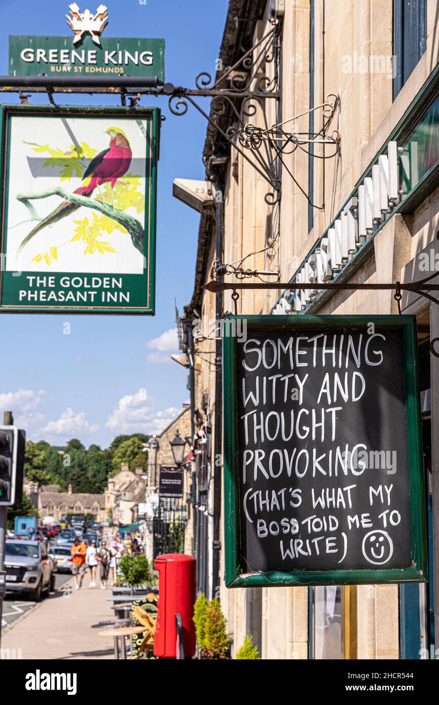 A funny sign outside a pub in the High Street of the Cotswold town of Burford, Oxfordshire UK Stock Photo