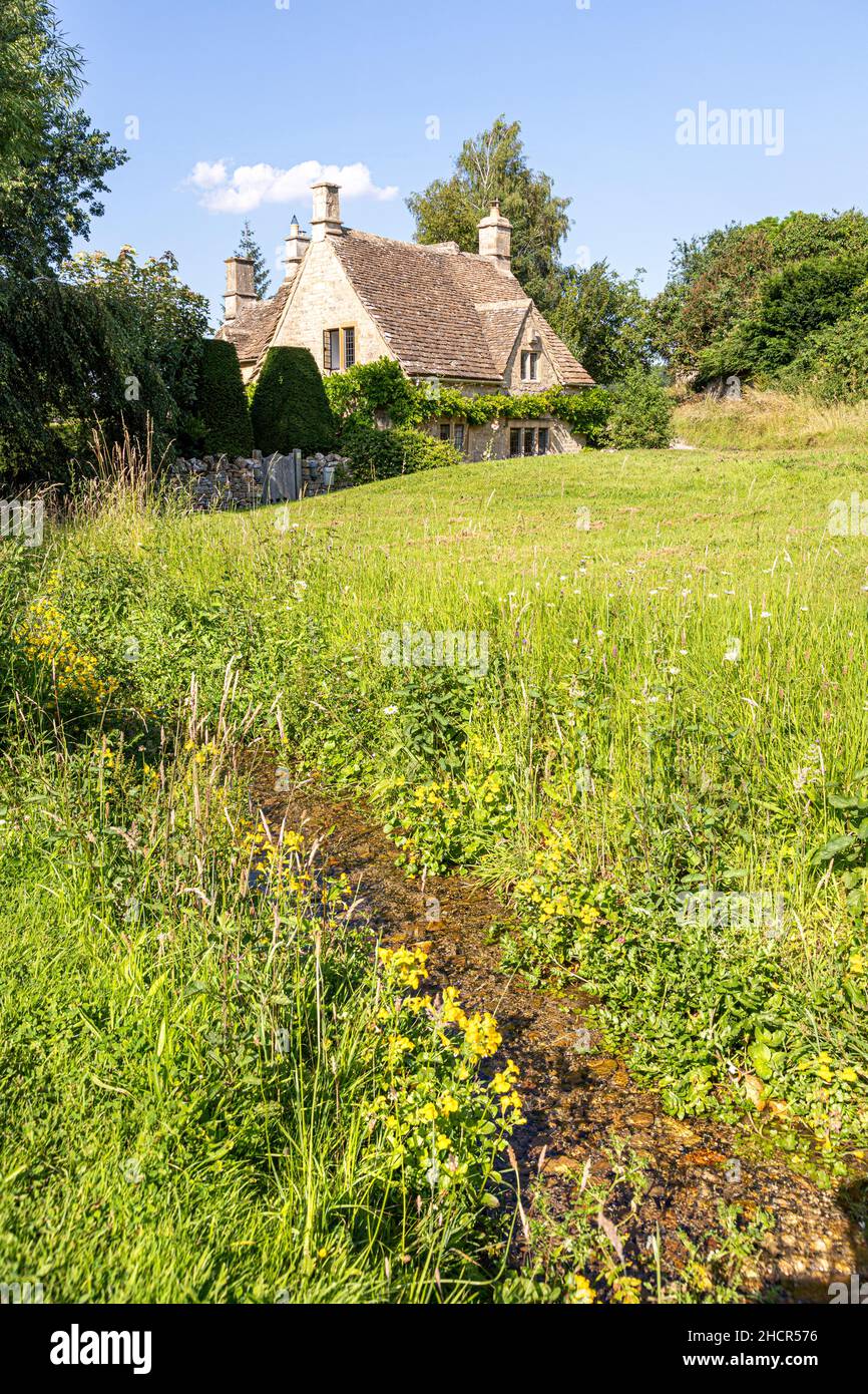 A traditional stone cottage beside the stream in the Cotswold village of Little Barrington, Gloucestershire UK Stock Photo