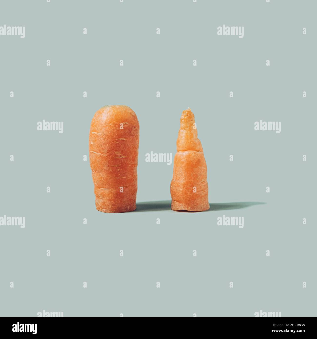 Fresh carrot sliced in half on a light green background. Healthy eating minimal concept Stock Photo
