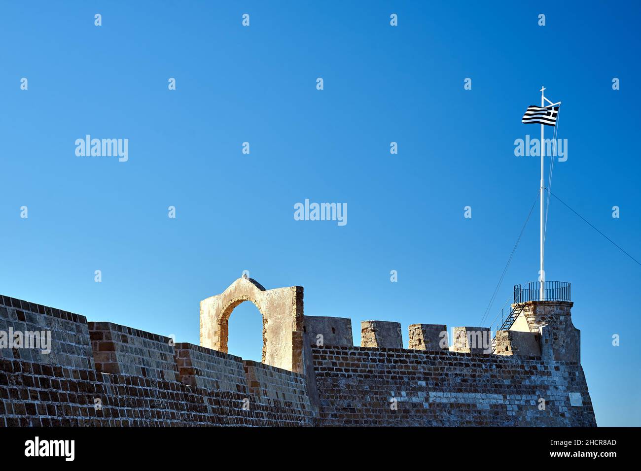 A bastion of a Venetian fortress with a Greek flag on a mast in the city of Chania on the island of Crete in Greece Stock Photo