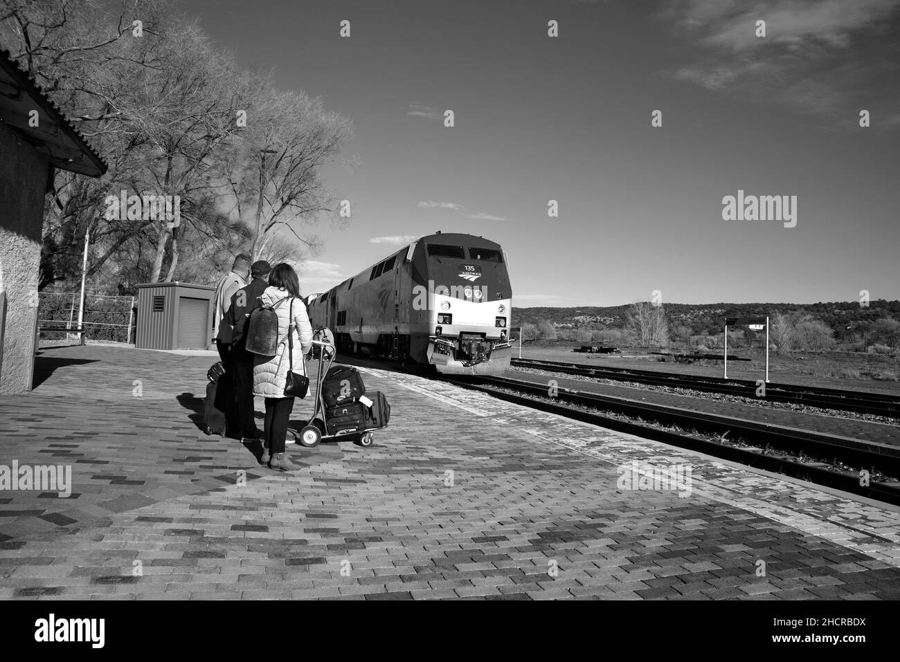 Passengers stand on the platform as an Amtrak passenger train (the Southwest Chief) arrives at the train station in Lamy, New Mexico. Stock Photo