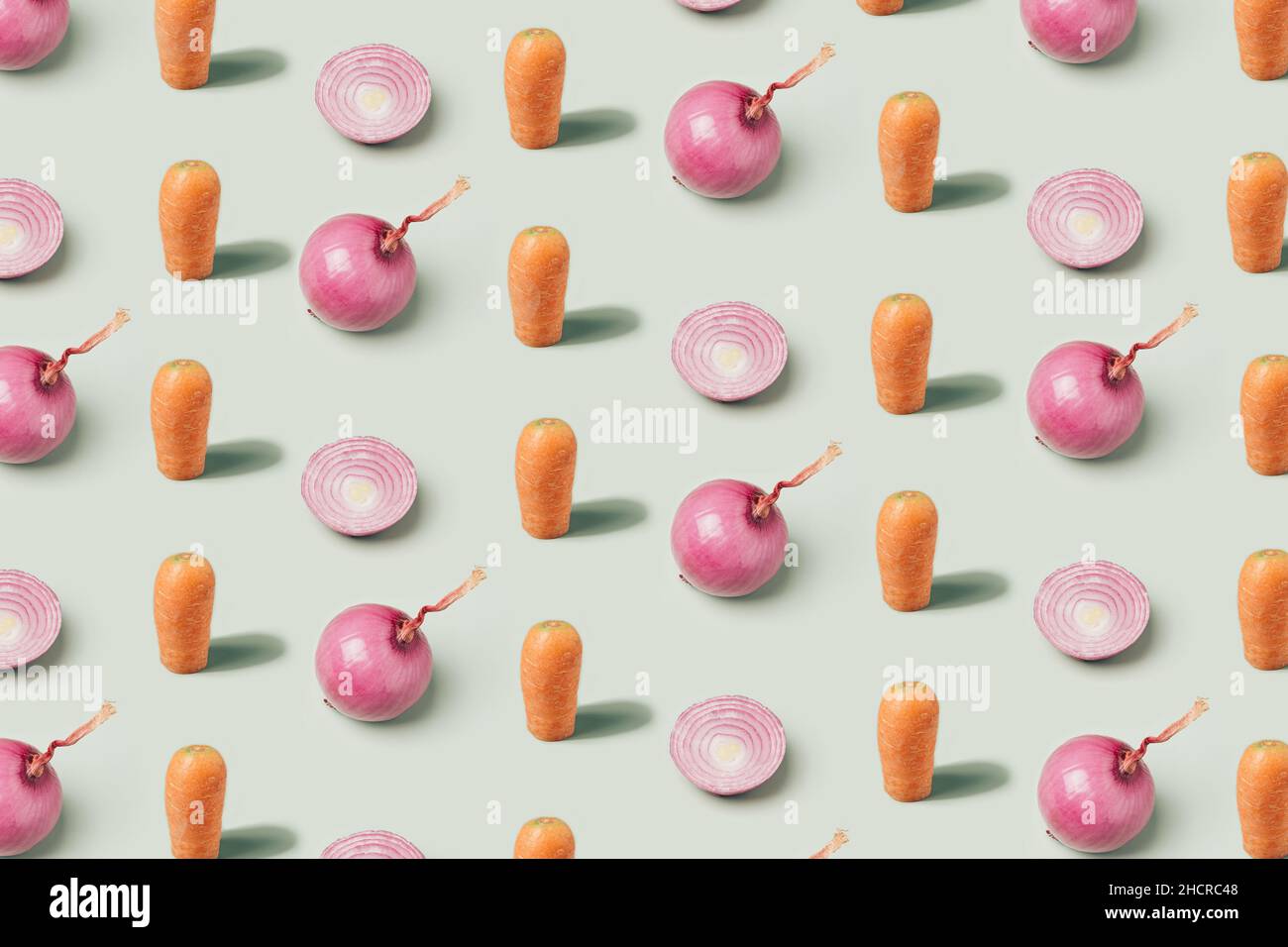 Carrots and red onions arranged on a pastel green background. Vegan diet minimal pattern Stock Photo