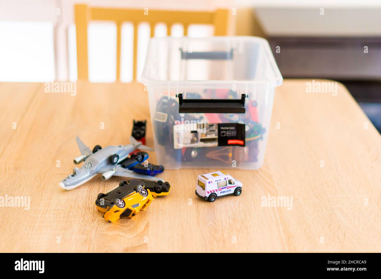 A plastic box with toy model cars and planes on a wooden table Stock Photo