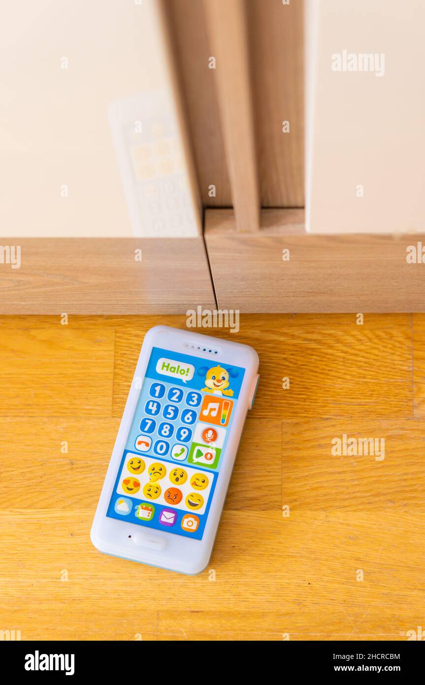 Fisher Price brand toy telephone with buttons and sounds laying on a floor next to a cupboard Stock Photo