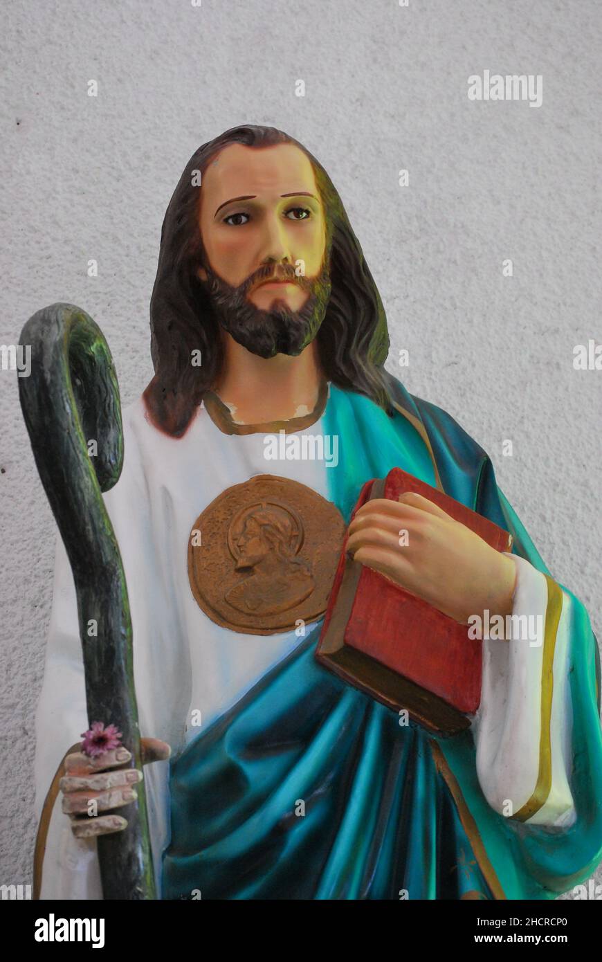 Closeup of a sculptured statue of Jesus holding the bible and a stick