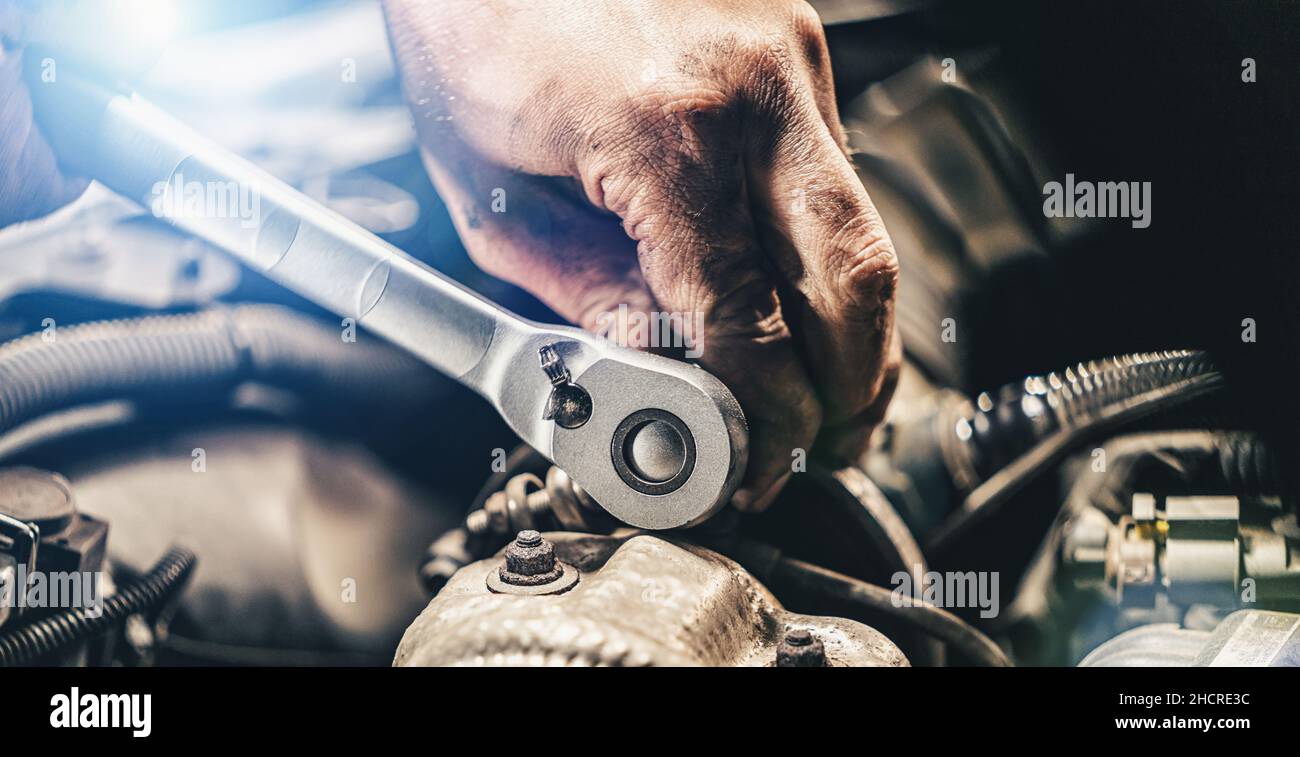 Auto mechanic hands working on car engine in mechanics garage. Repair