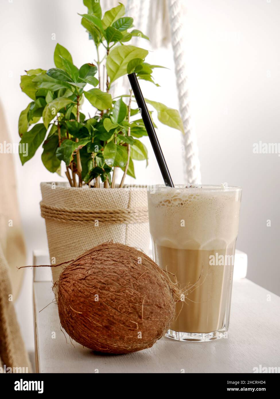 Coconut latte in a tall glass and coconut on a swing in a cafe. Close up. Stock Photo