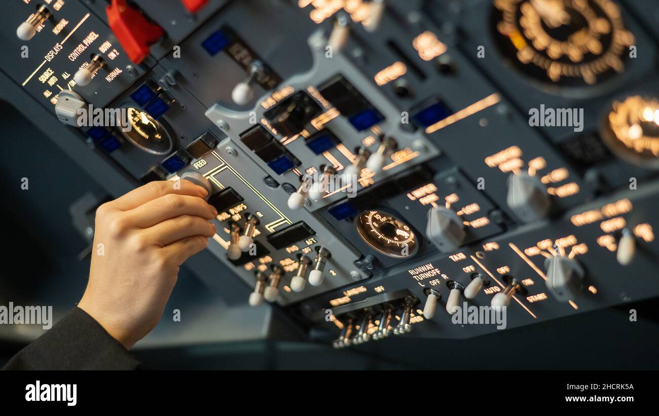Close-up of a pilot's hand turning a toggle switch on the control panel ...