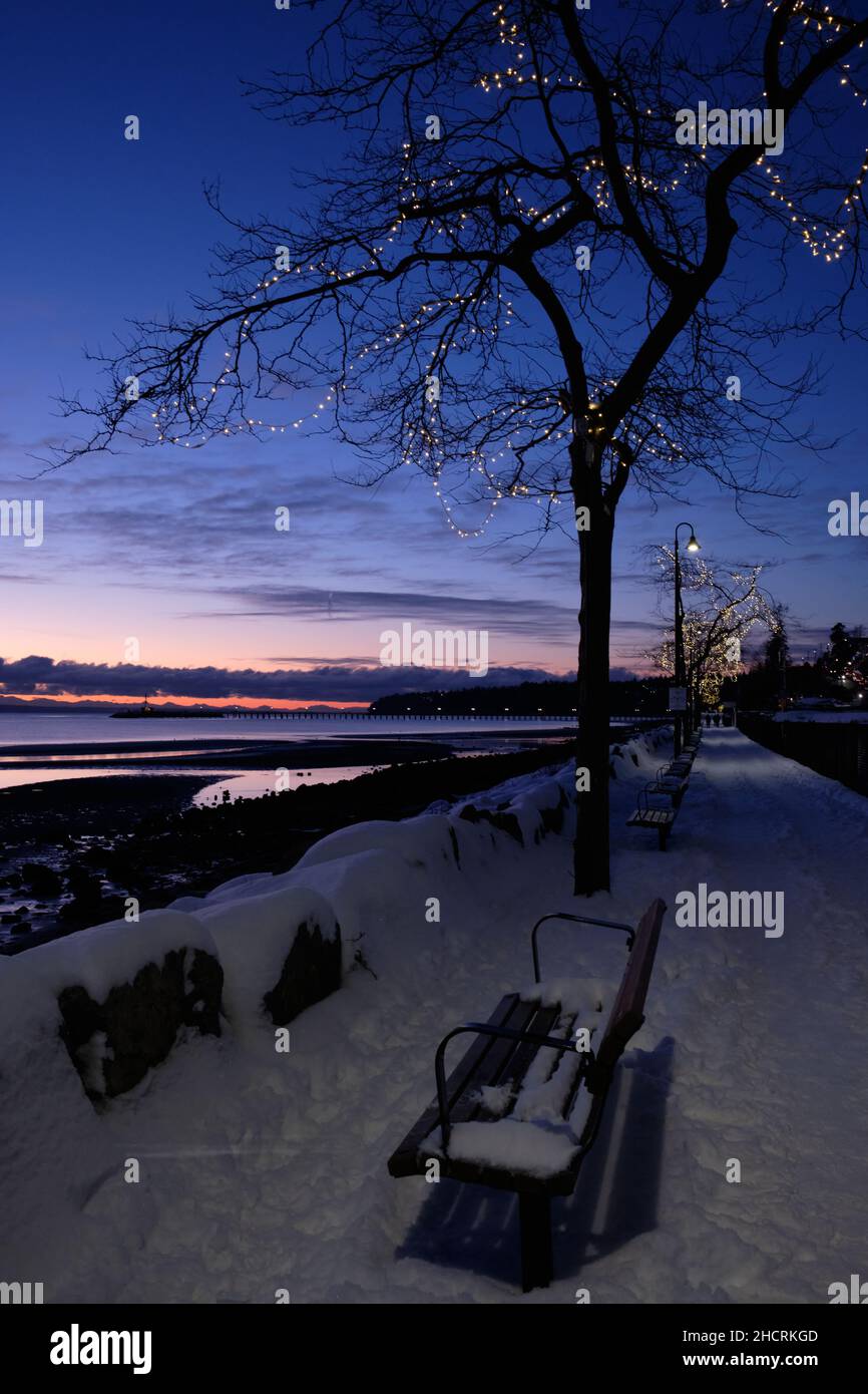Empty benches and snow-covered promenade.  Waterfront in White Rock, BC after December snowfall Stock Photo