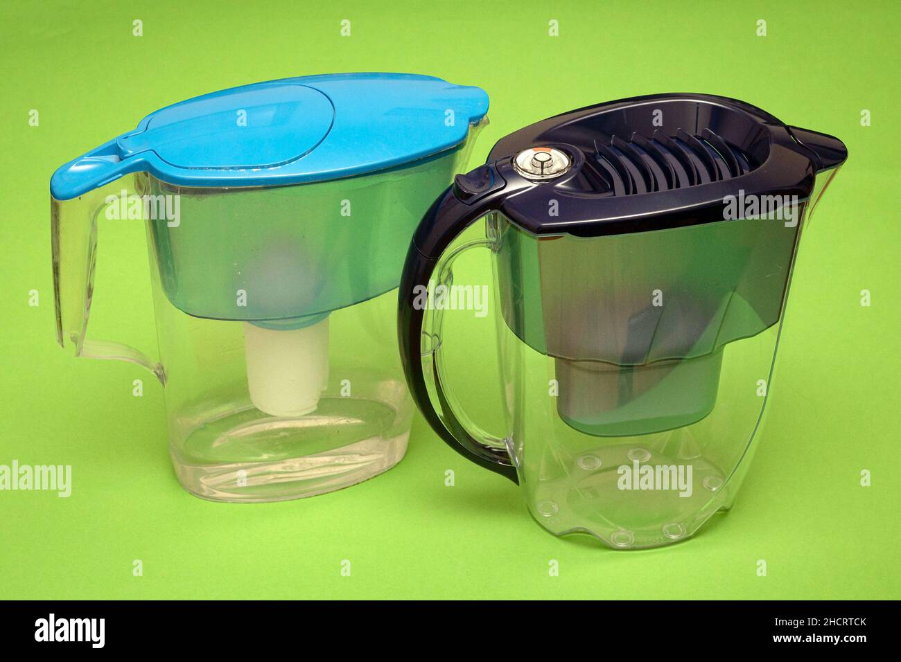Plastic jugs for water filtering at home on green background Stock