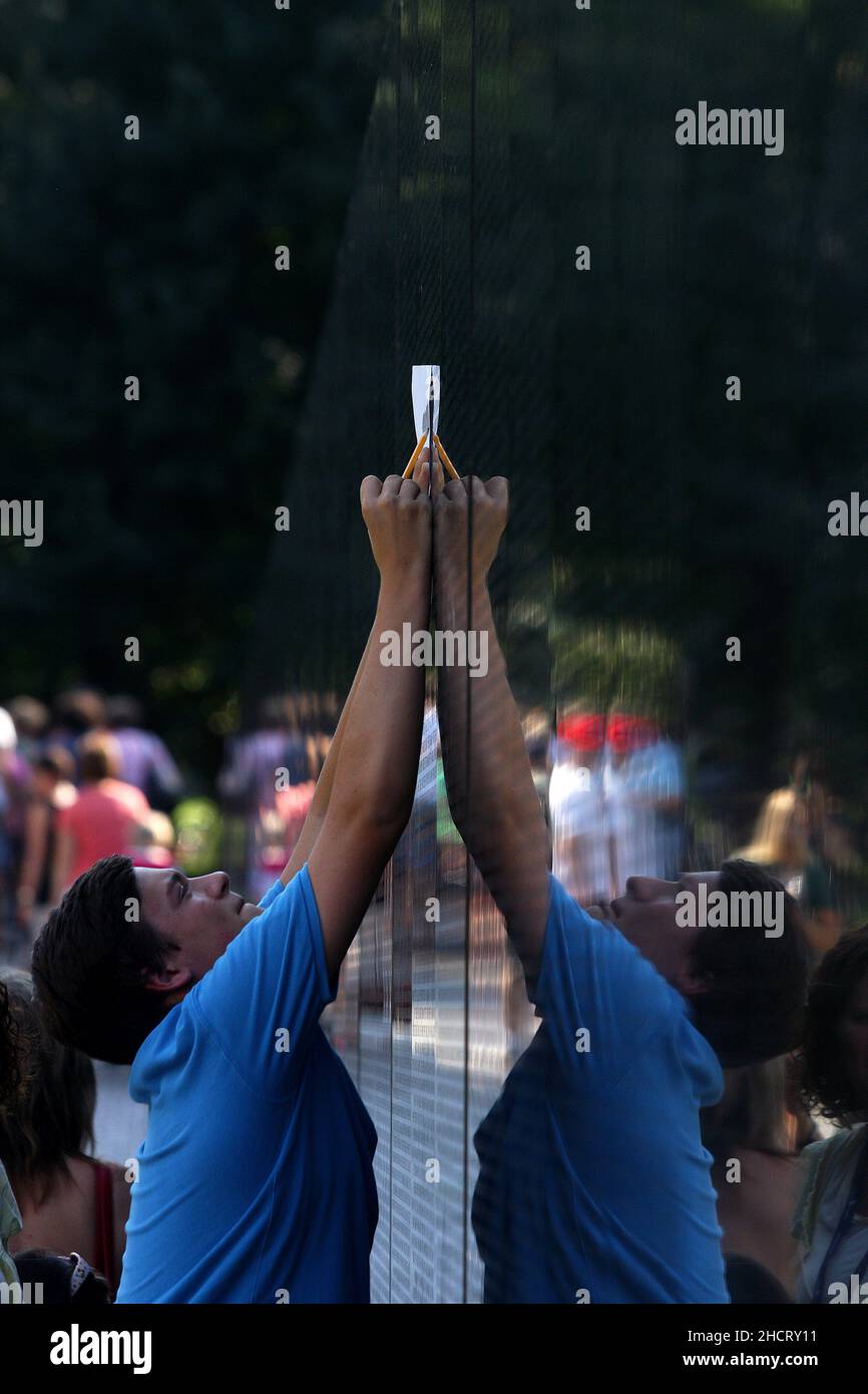 Visitors to the Vietnam Veterans Memorial in Washington, D.C. touch the names of those who died in the war which are engraved on the polished stone face of the memorial.  The memorial was designed by Maya Lin. Stock Photo