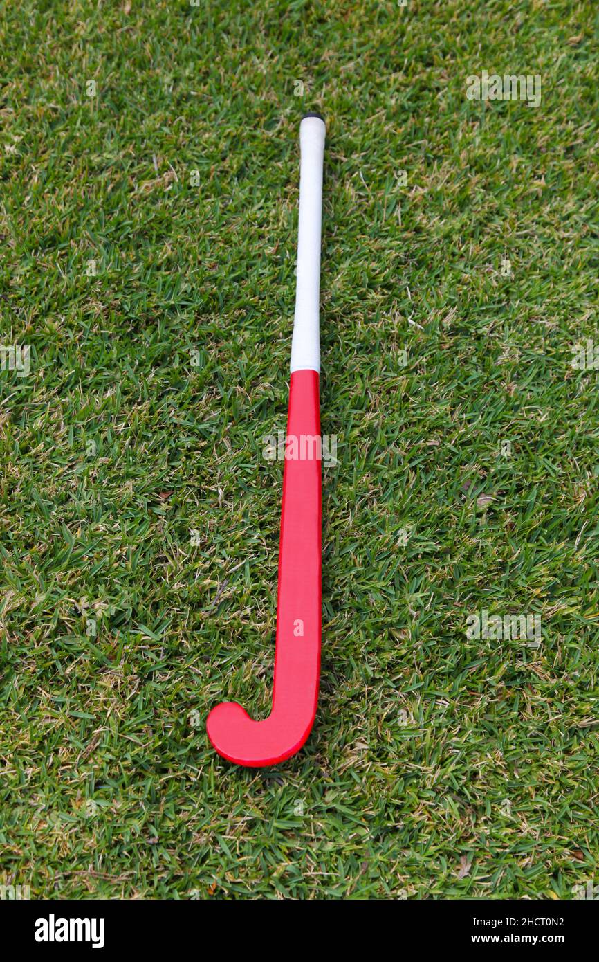 A red field hockey stick on green grass background. Stock Photo