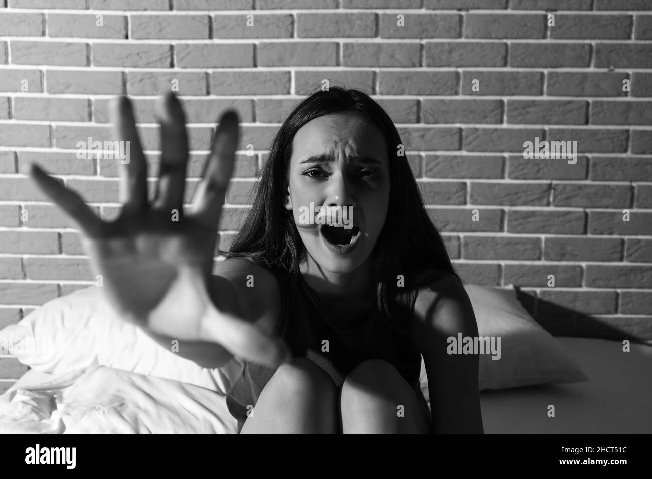 Scared young woman on bed. Violence concept Stock Photo
