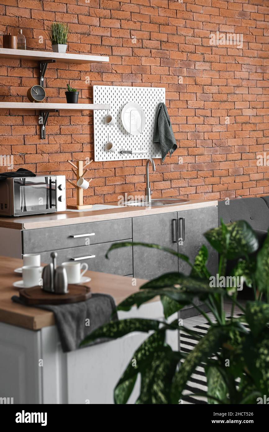 Interior of modern kitchen with counters and hanging pegboard on brick ...