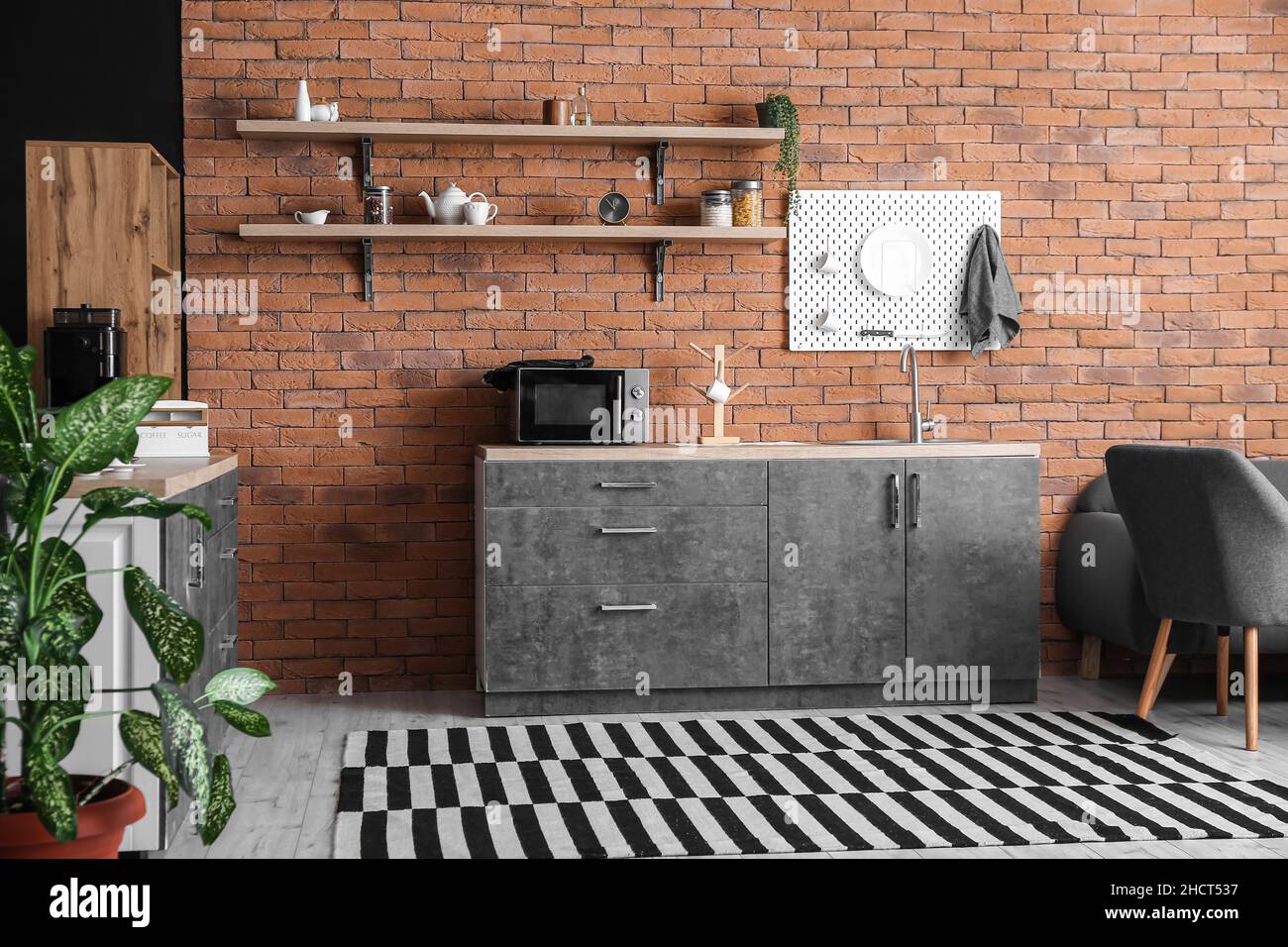 Interior of modern kitchen with counters and hanging pegboard on brick ...