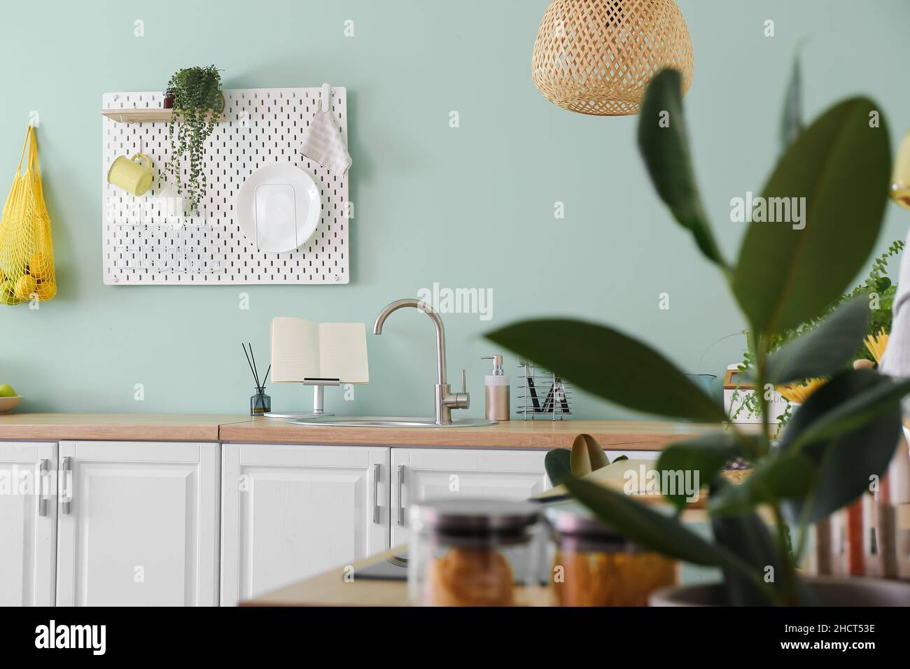Interior of stylish kitchen with white counters and hanging peg board ...
