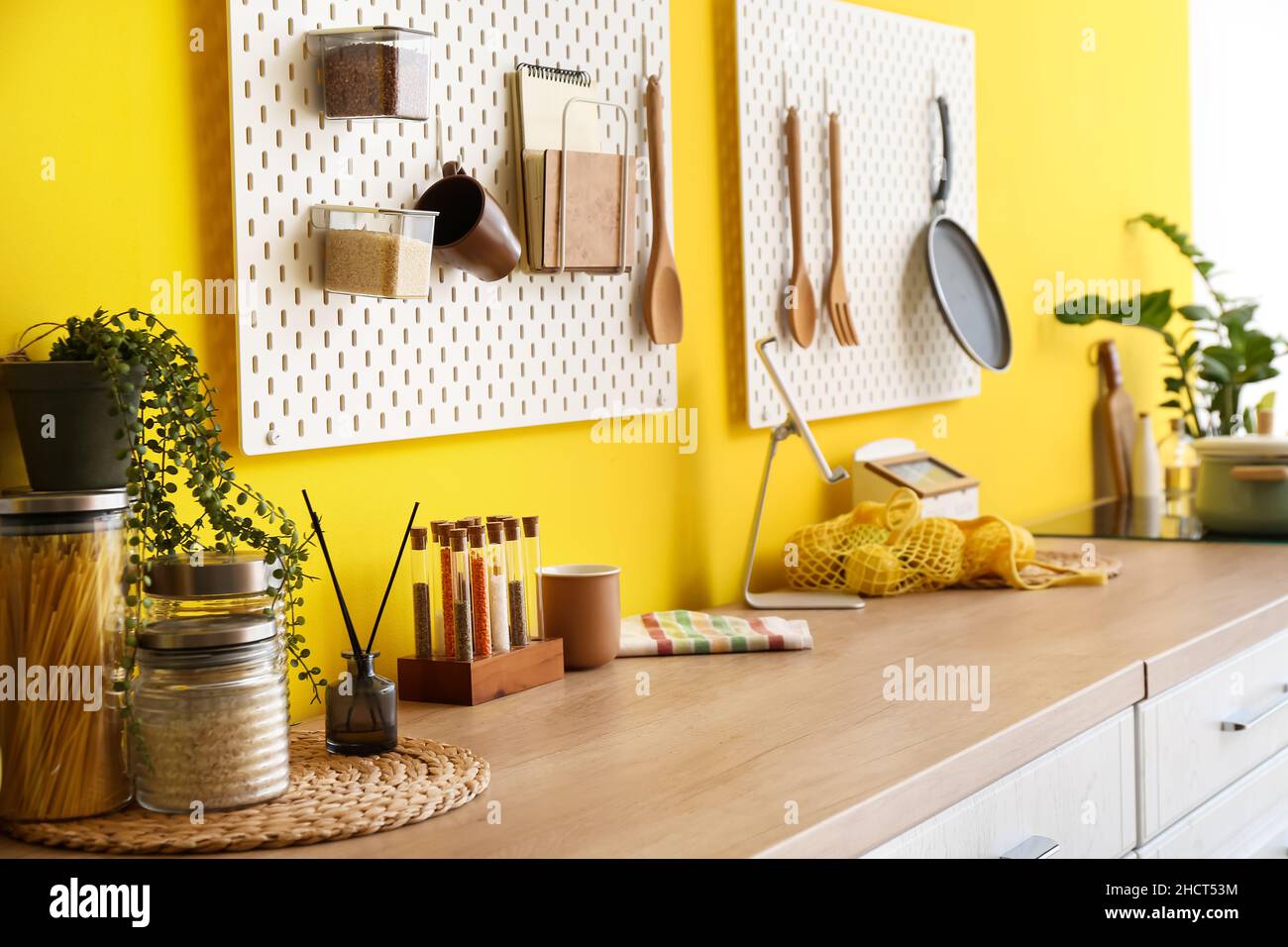 Peg boards with kitchenware hanging on yellow wall Stock Photo