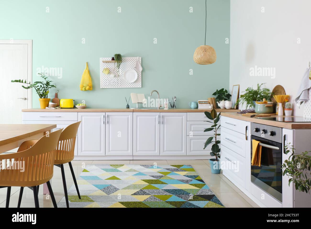 Interior of stylish kitchen with white counters and hanging peg board ...