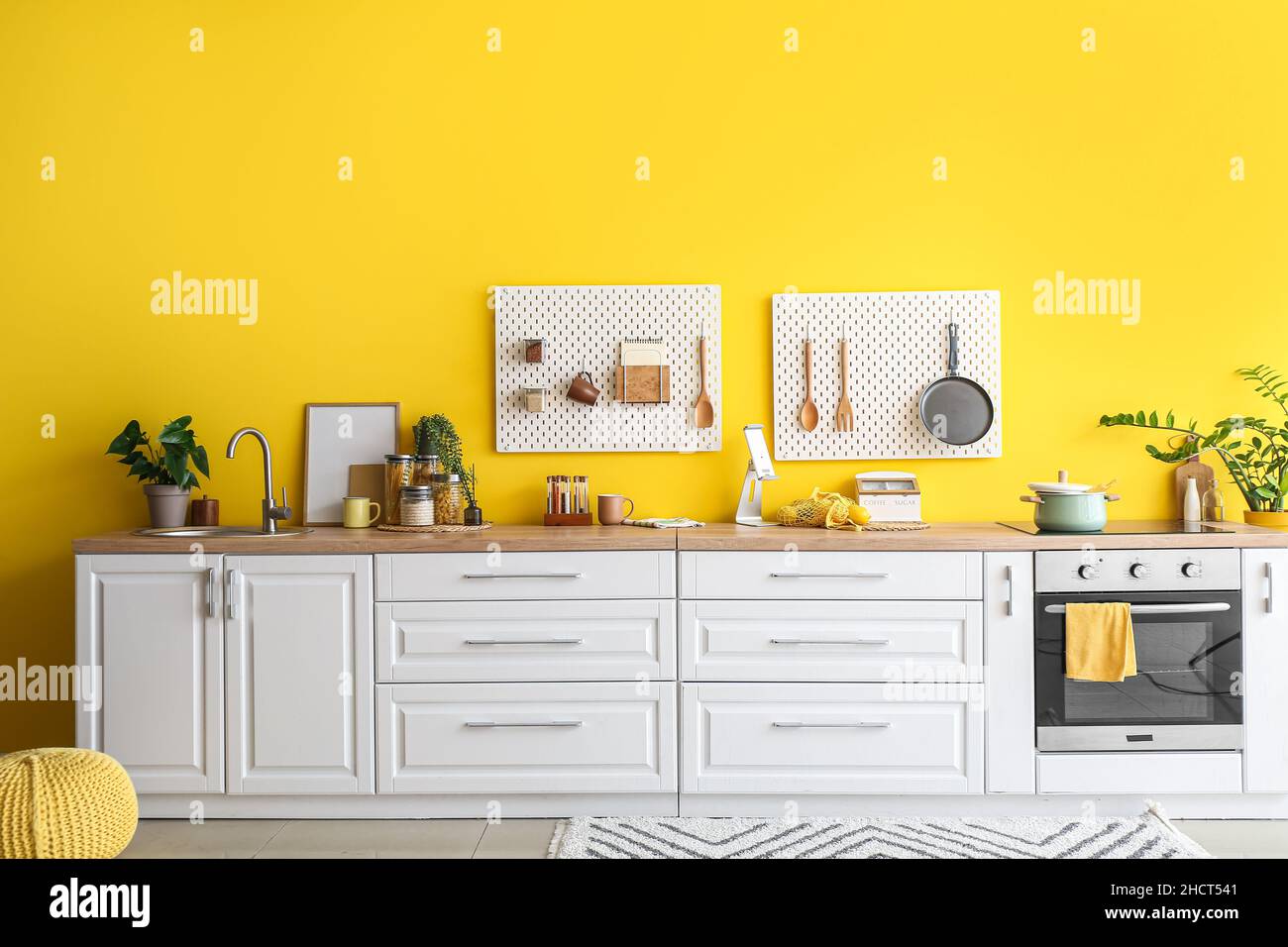 Interior of stylish kitchen with white counters, peg boards and yellow ...