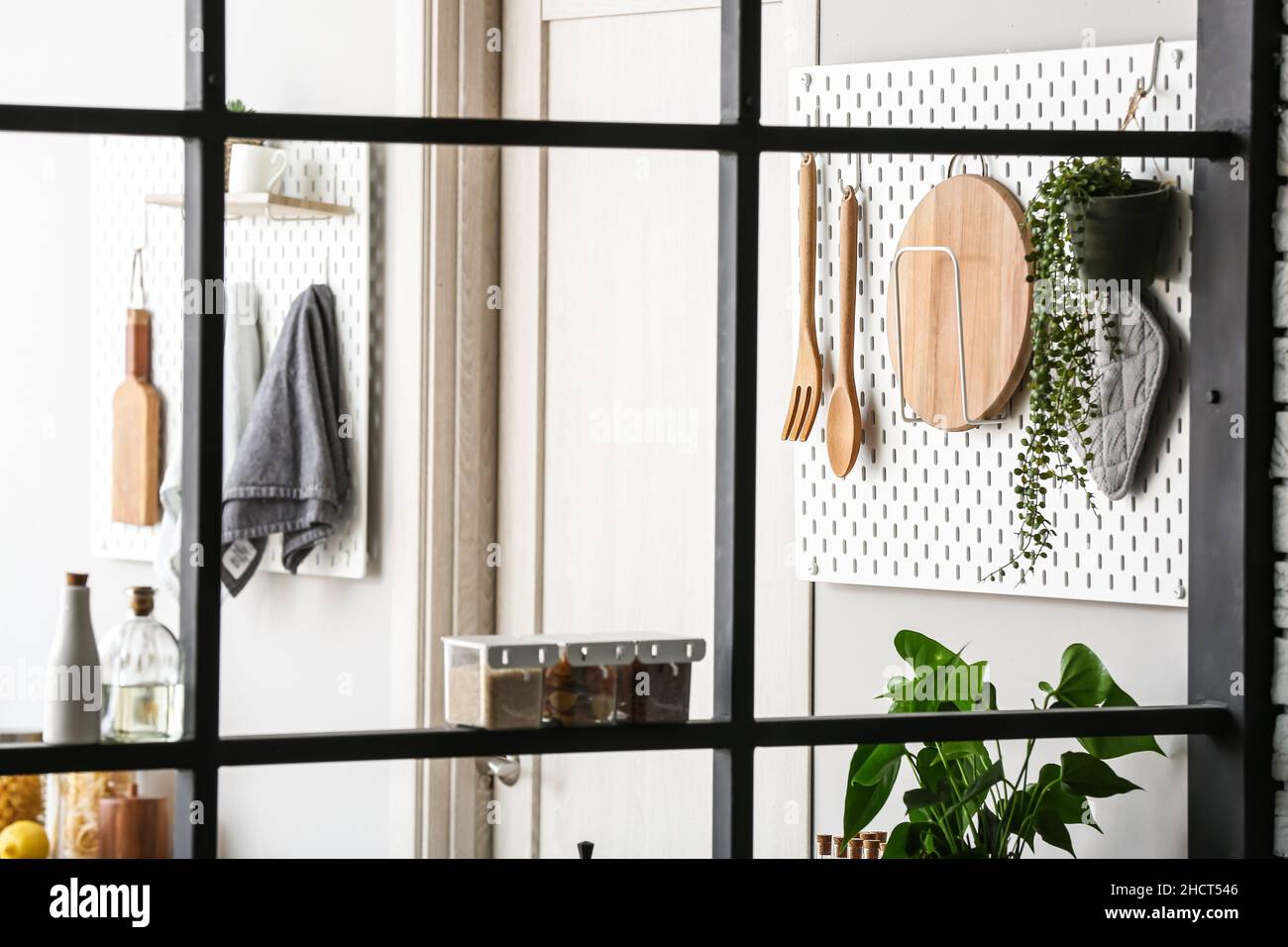 Peg boards with kitchenware hanging on light wall Stock Photo