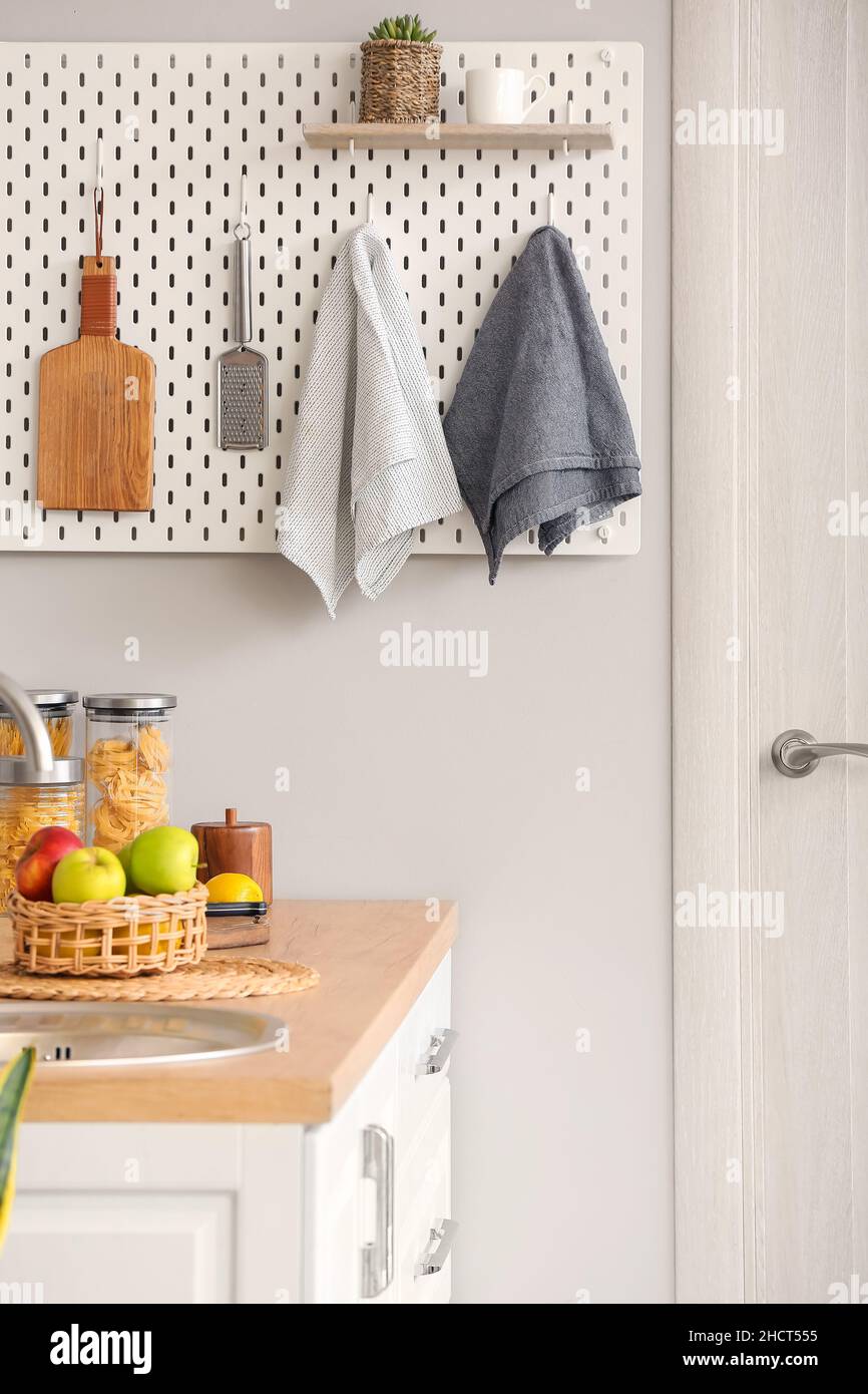 Peg board with kitchenware hanging on light wall Stock Photo