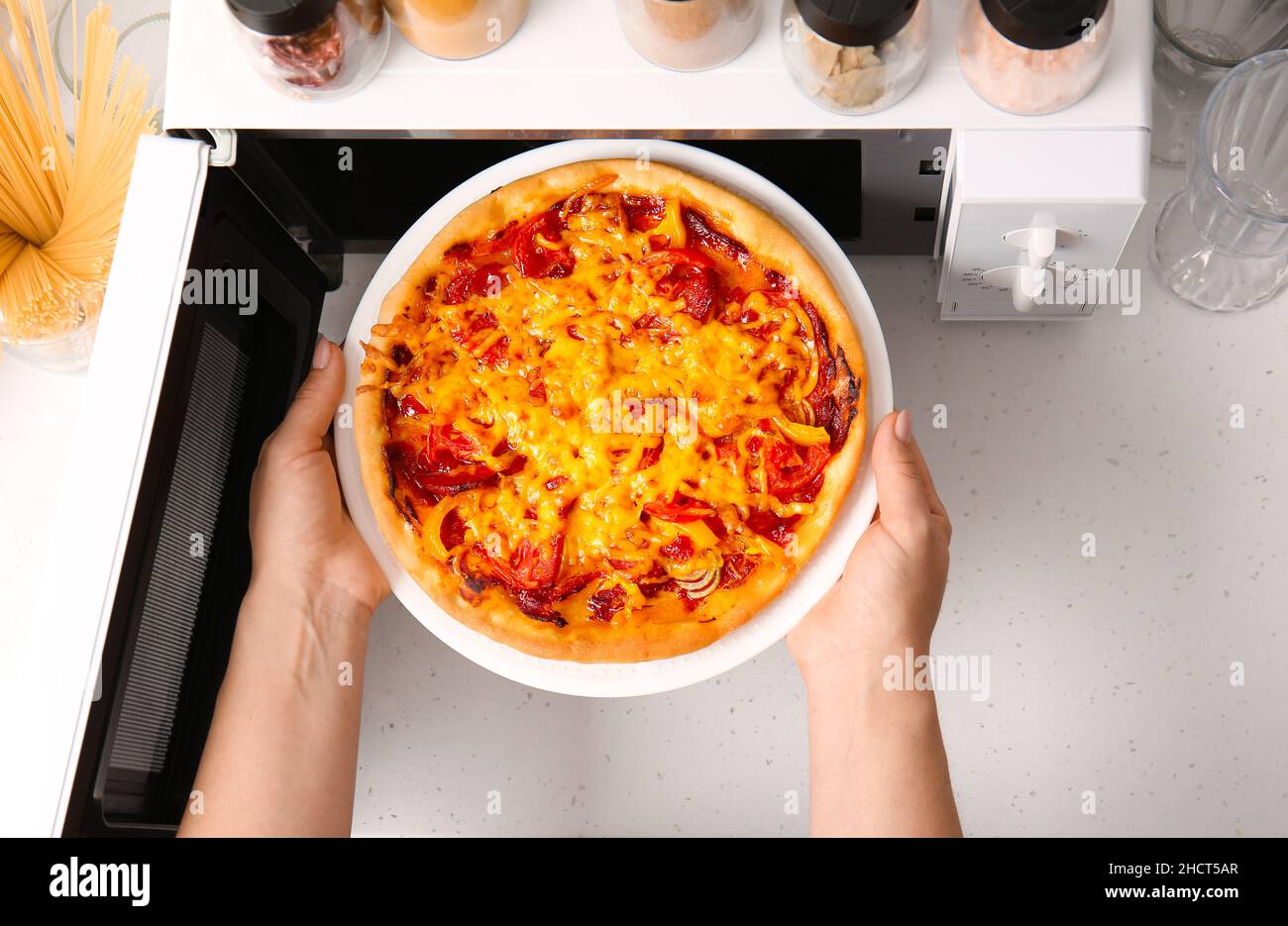 https://c8.alamy.com/comp/2HCT5AR/woman-putting-plate-with-pizza-into-microwave-oven-in-kitchen-closeup-2HCT5AR.jpg