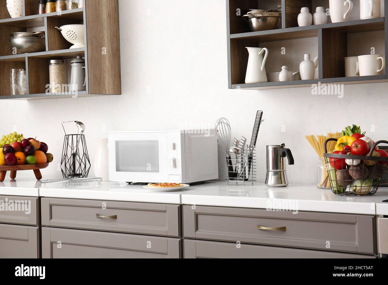 Interior of light kitchen with counters, microwave oven and utensils