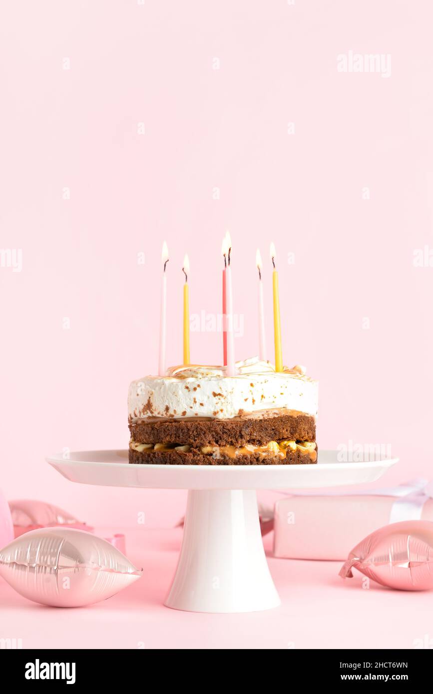 Stand with tasty birthday cake and balloons on pink background Stock ...