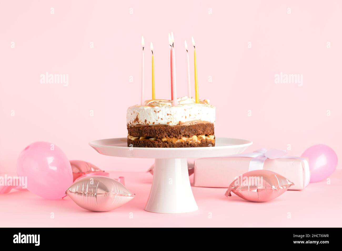 Stand with tasty birthday cake and balloons on pink background Stock ...