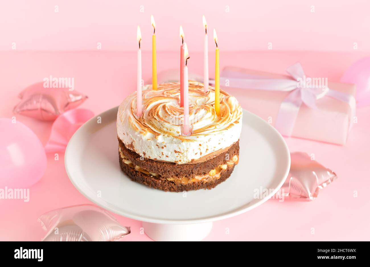 Stand with tasty birthday cake and balloons on pink background Stock ...