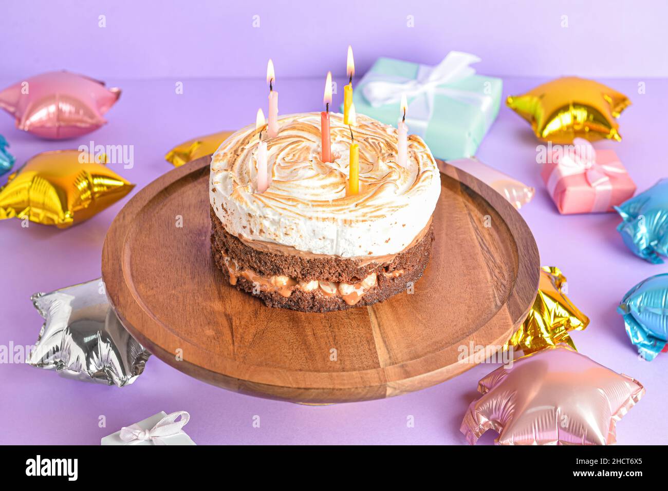 Stand with tasty birthday cake and balloons on purple background Stock ...