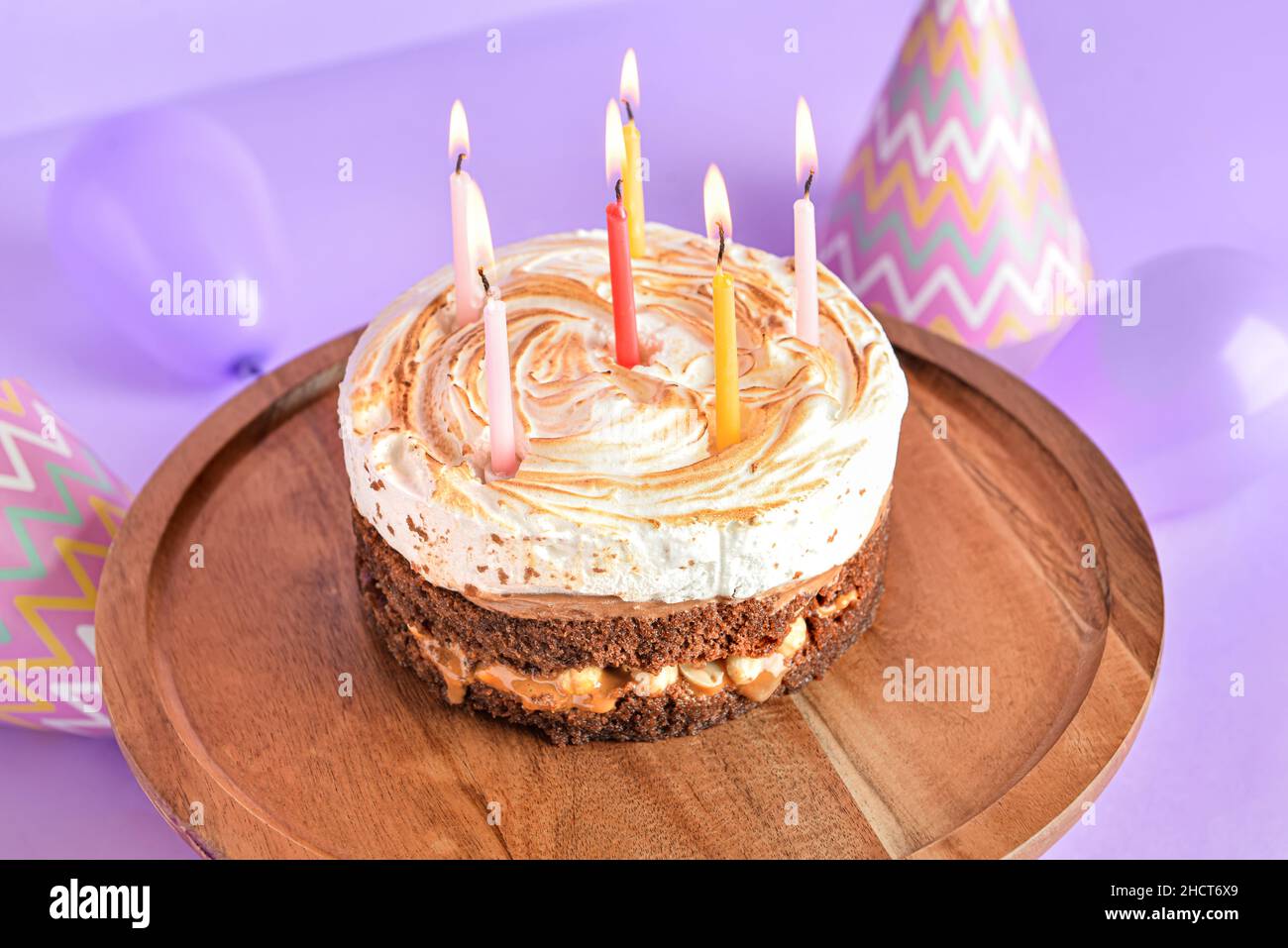 Stand with tasty birthday cake and burning candles on purple background ...