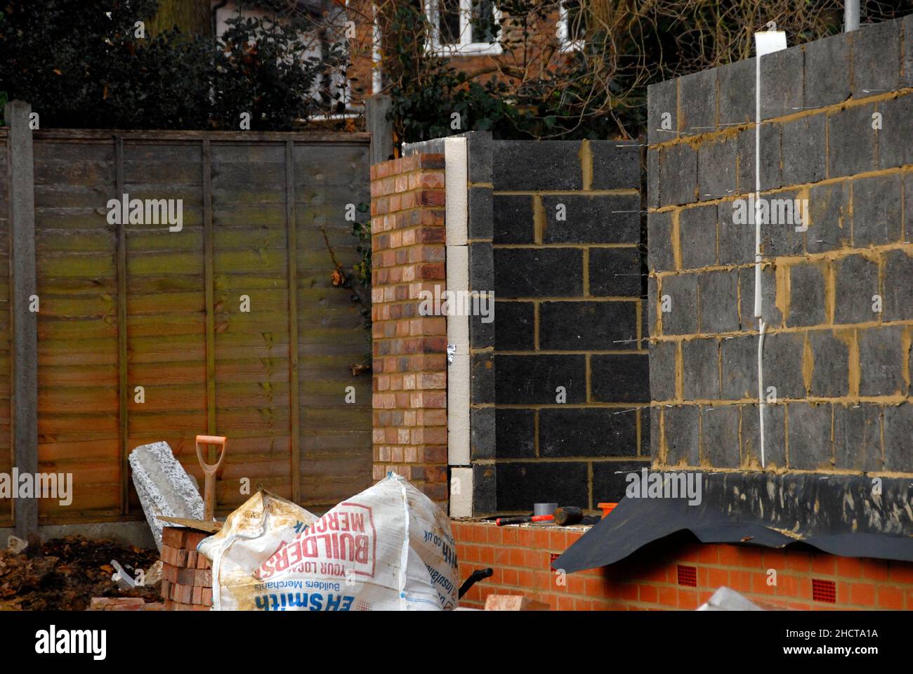 Building site with house under construction showing outer wall made of bricks and inner wall from breeze blocks with thick layer of insulation between Stock Photo