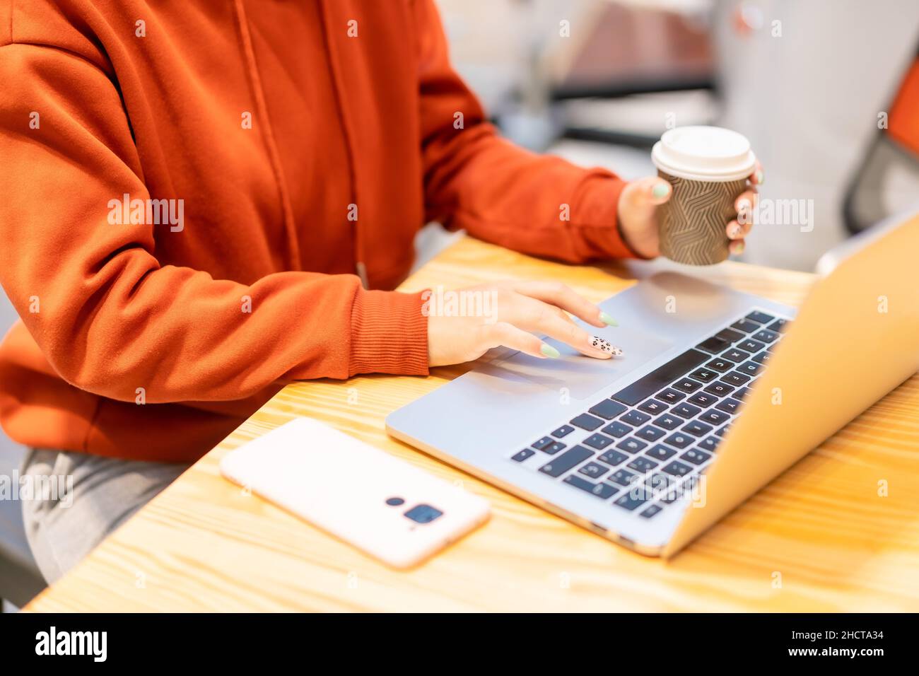 Alternative unrecognizable person with a coffee surfing the internet on the computer Stock Photo